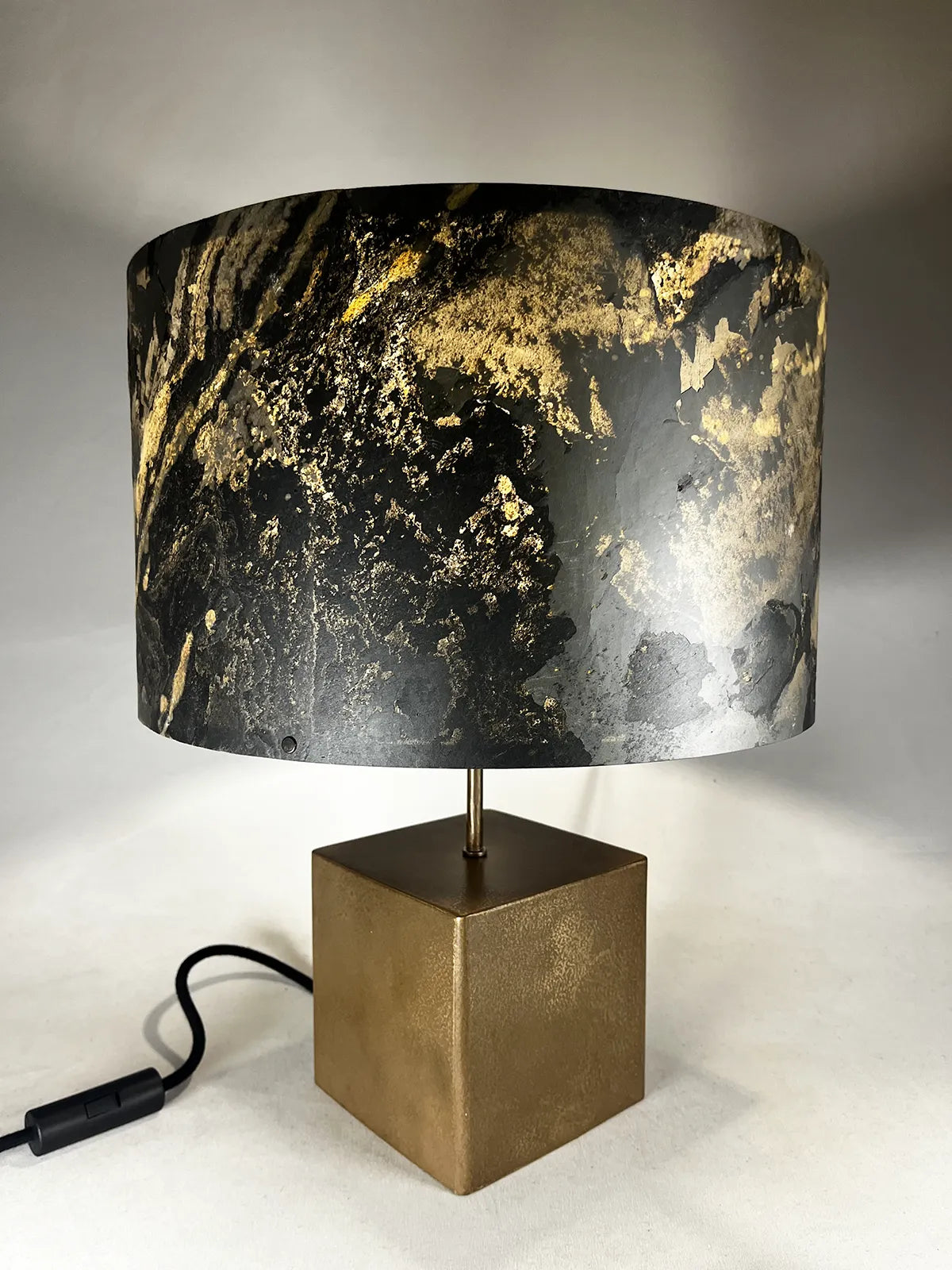 Vue plongée de la lampe en acier revêtu de poudre de bronze et son abat-jour en feuille d'ardoise rustique allumée, modèle Cassini au style minimaliste wabi-sabi par l'atelier Maus