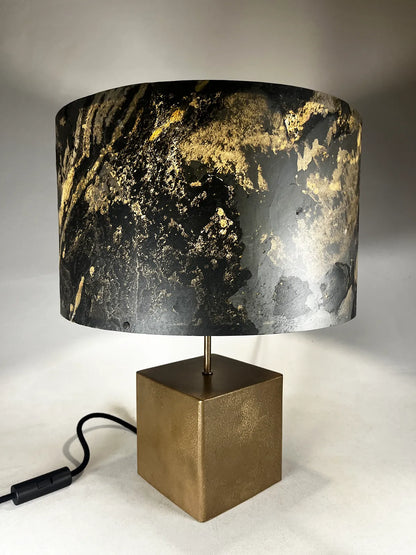 Vue plongée de la lampe en acier revêtu de poudre de bronze et son abat-jour en feuille d'ardoise rustique allumée, modèle Cassini au style minimaliste wabi-sabi par l'atelier Maus