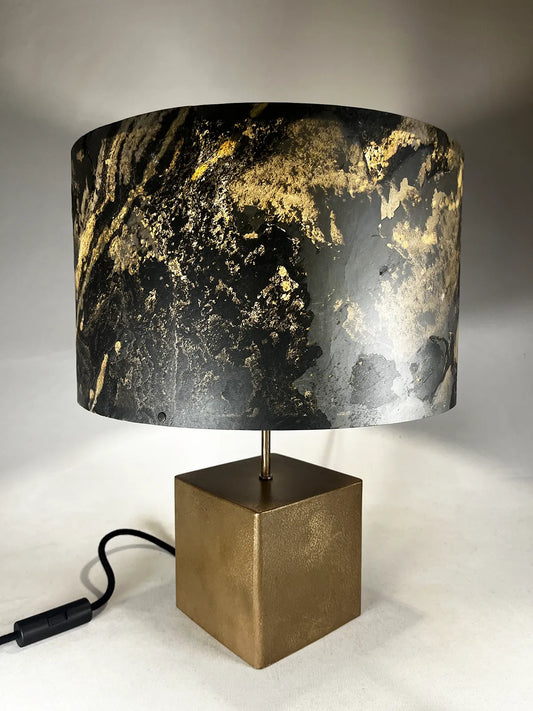 Vue plongée de la lampe en acier revêtu de poudre de bronze et son abat-jour en feuille d'ardoise rustique allumée, modèle Cassini au style minimaliste wabi-sabi par l'atelier Maus