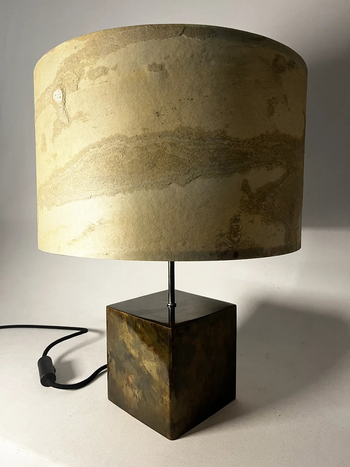 vue de la lampe Cassini en acier patiné et  feuille d'ardoise nuancée de beiges, ocres et brun, son cordon électrique gainé de coton noir et son interrupteur cylindrique noir