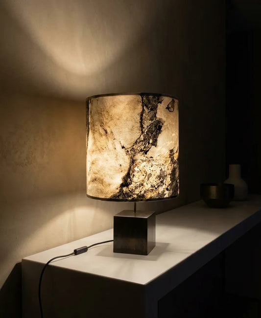 Lampe Cassini Nova en acier patiné et feuille d'ardoise rustique en situation sur un meuble en pierre contre un mur en béton ciré