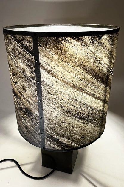 vue arrière de la lampe Cassini Nova allumée – diffusion lumière enveloppante à travers feuille d'ardoise zébrée, ambiance minérale style wabi-sabi
