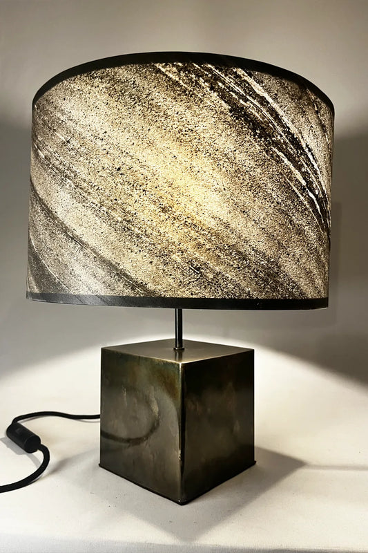 Vue de profil lampe Cassini Aura – zébrures minérales de l'ardoise naturelle et patine noire brune irisée du pied en acier