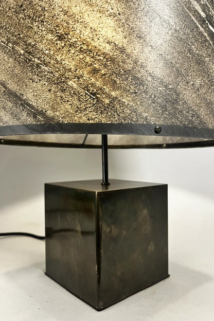 Lampe à poser artisanale Cassini Aura – abat-jour ardoise zébrée translucide éclairé, reflets irisés sur le piètement acier patiné