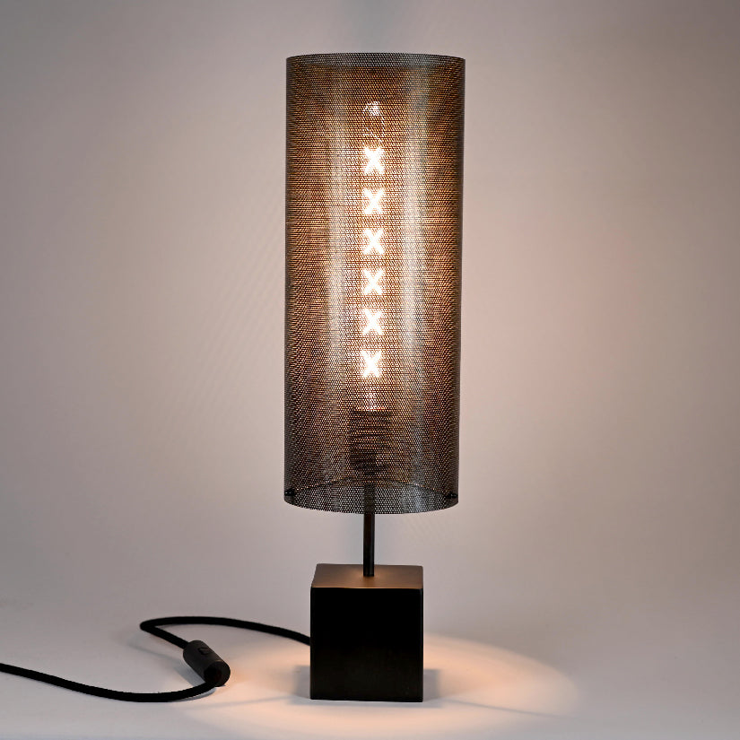 Lampe Halley Halo allumée diffusant une lumière douce et tamisée à travers la tôle perforée