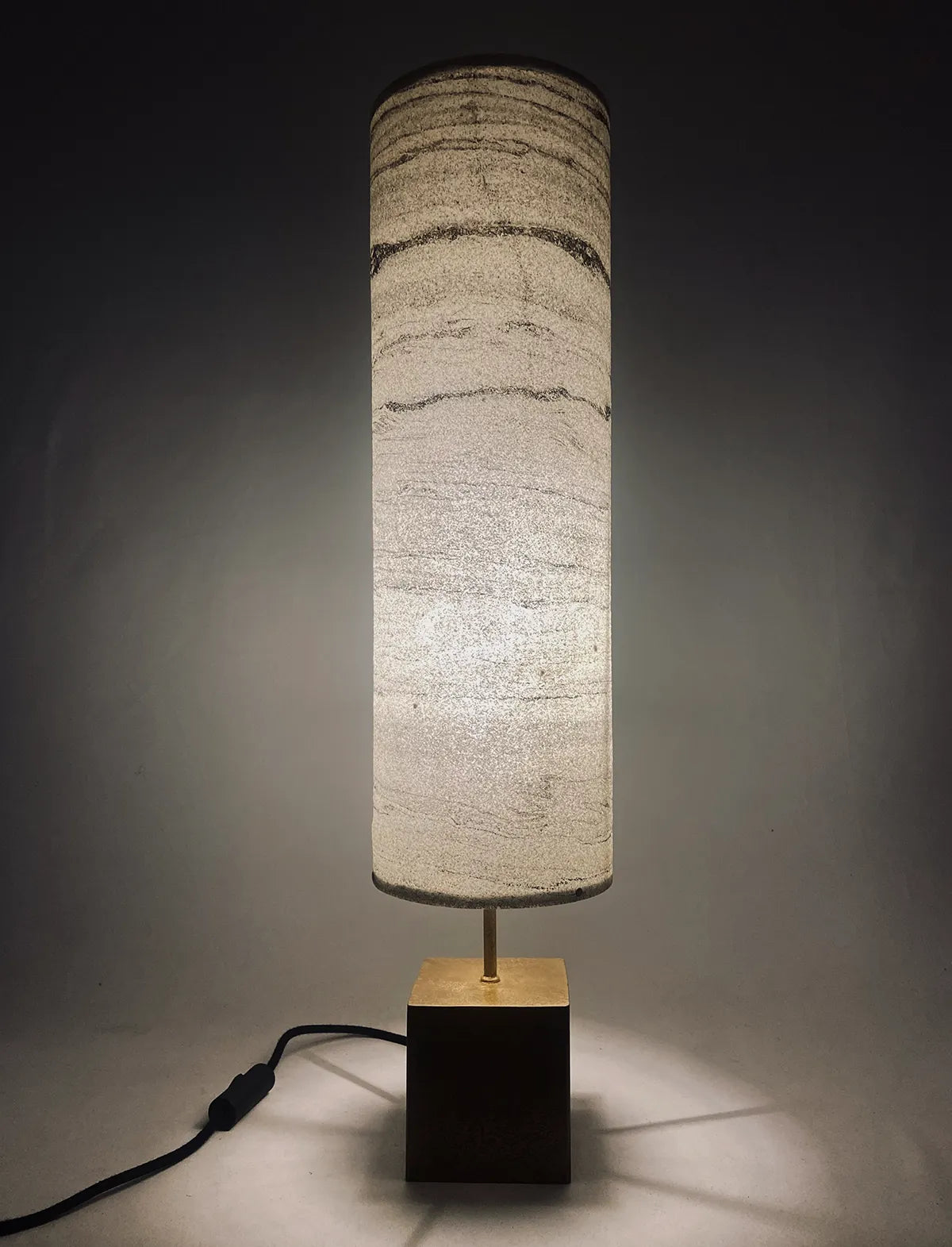 Vue  de la lampe en acier laitonné et abat-jour en marbre statuario allumée. pièce unique de l'atelier Maus. Fabriqué en France