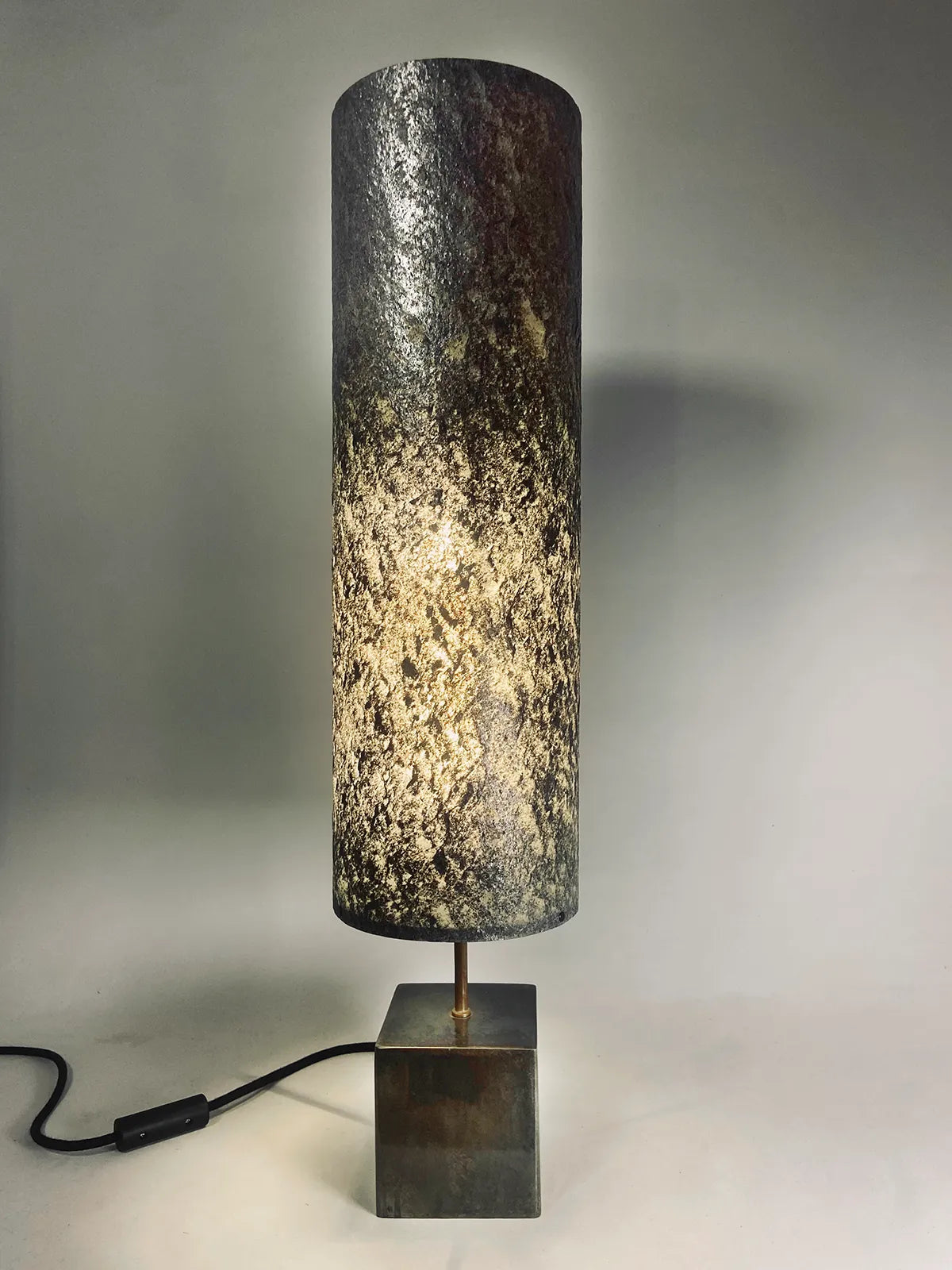 Vue de la Lampe en acier patiné  et feuille de mica argenté allumée. création oriinale de l'atelier Maus. Fabriqué en France