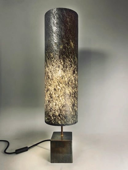 Vue de la Lampe en acier patiné  et feuille de mica argenté allumée. création oriinale de l'atelier Maus. Fabriqué en France