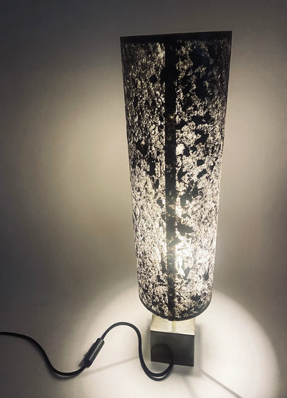 Vue arrière de la Lampe artisanale unique en acier patiné  et feuille de mica argenté allumée. création originale de l'atelier Maus. Fabriqué en France