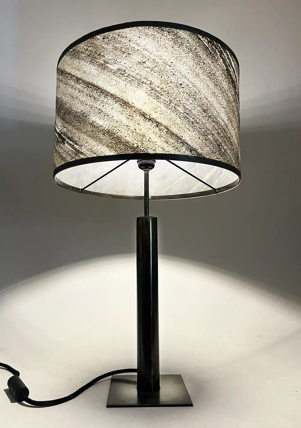 Vue en contre plongée de la lampe en acier patiné et son abat-jour en ardoise zébrée. création artisanale design, modèle Rosalynd par l'atelier Maus