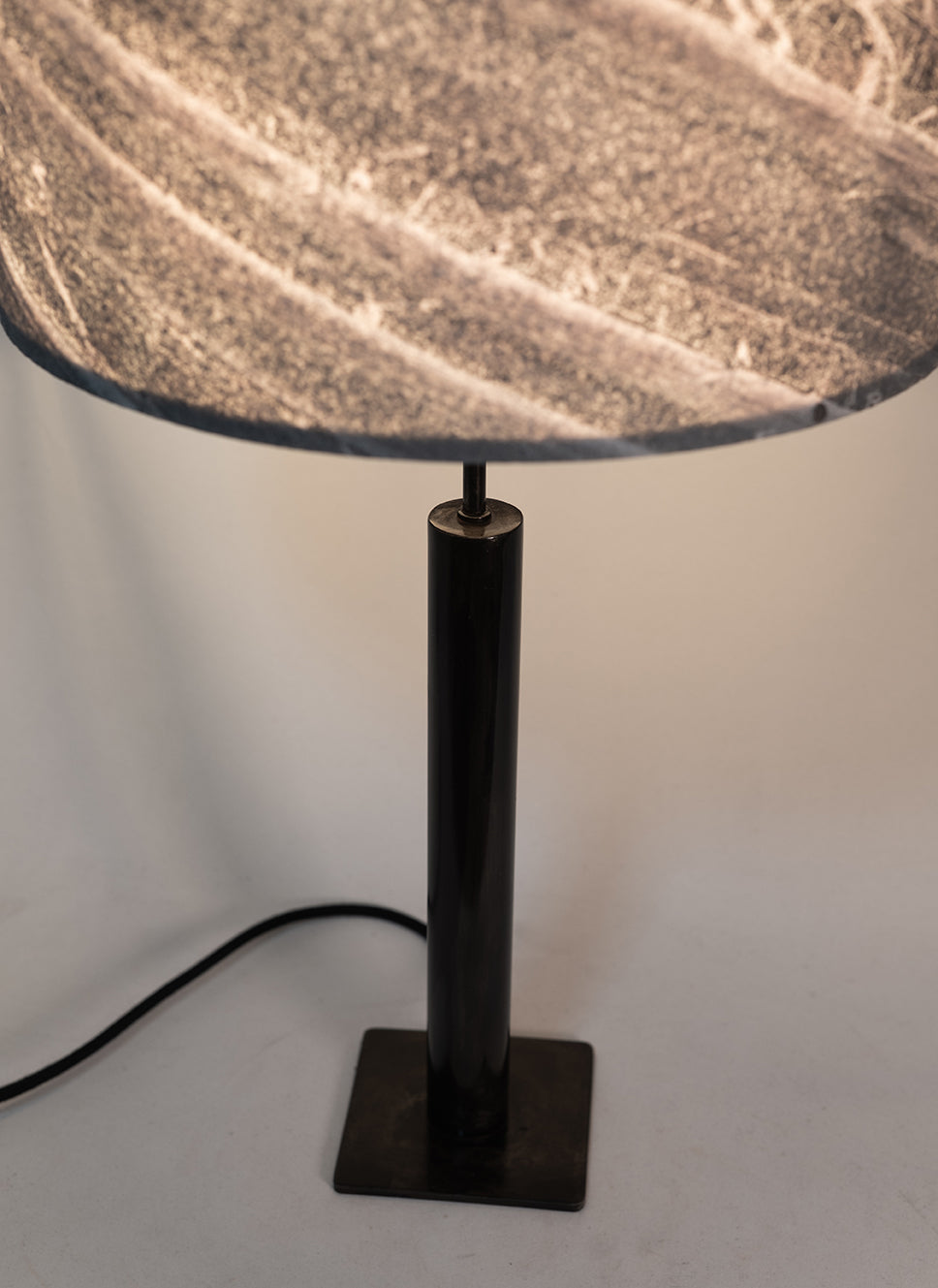 Photo en gros plan de la lampe Rosalynd en acier patiné et feuille de marbre allumée | Atelier Maus