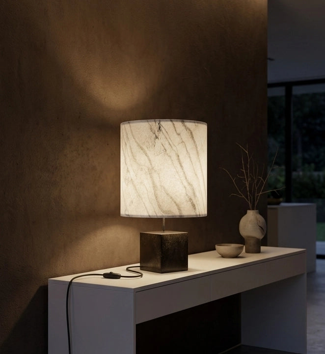 Lampe Cassini Nova en acier patiné brun noir , abat-jour en feuille de  marbre statuaire sur une console dans un intérieur contemporain design. Pièce unique de Fabrication française Atelier Maus