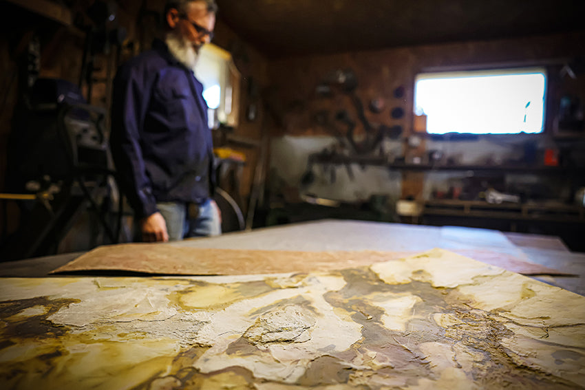 Photo de Stéphane Mausmond dans son atelier montrat des feuilles de pierres au premier plan | Atelier Maus