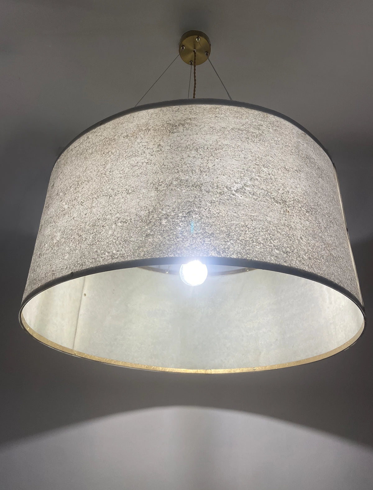 gros plan sur la suspension en feuille de mica vert gris naturelle de 63 cm allumée - Collection Thessalie de l'atelier Maus - Pièce unique de fabrication artisanale française