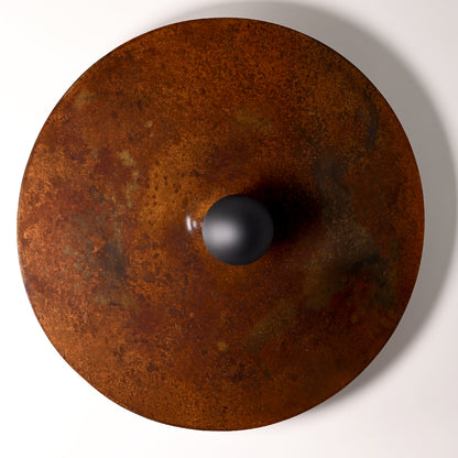 Gros plan sur la texture et les nuances de la finition rouille de l'applique Rovelli en acier oxydé