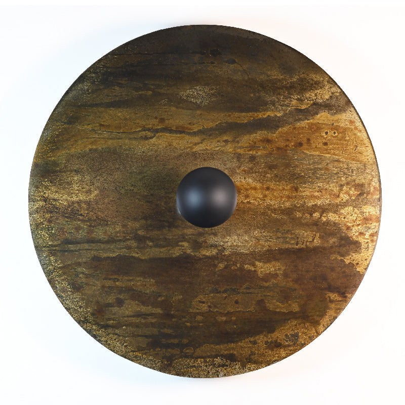 Gros plan sur les nuances de brun, doré et vert de gris de la finition oxydée de l'applique Rovelli