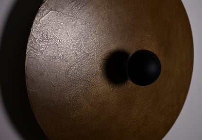 Détail de la finition poudre de laiton et des effets de matière de l'applique Rovelli ampoule deco noire