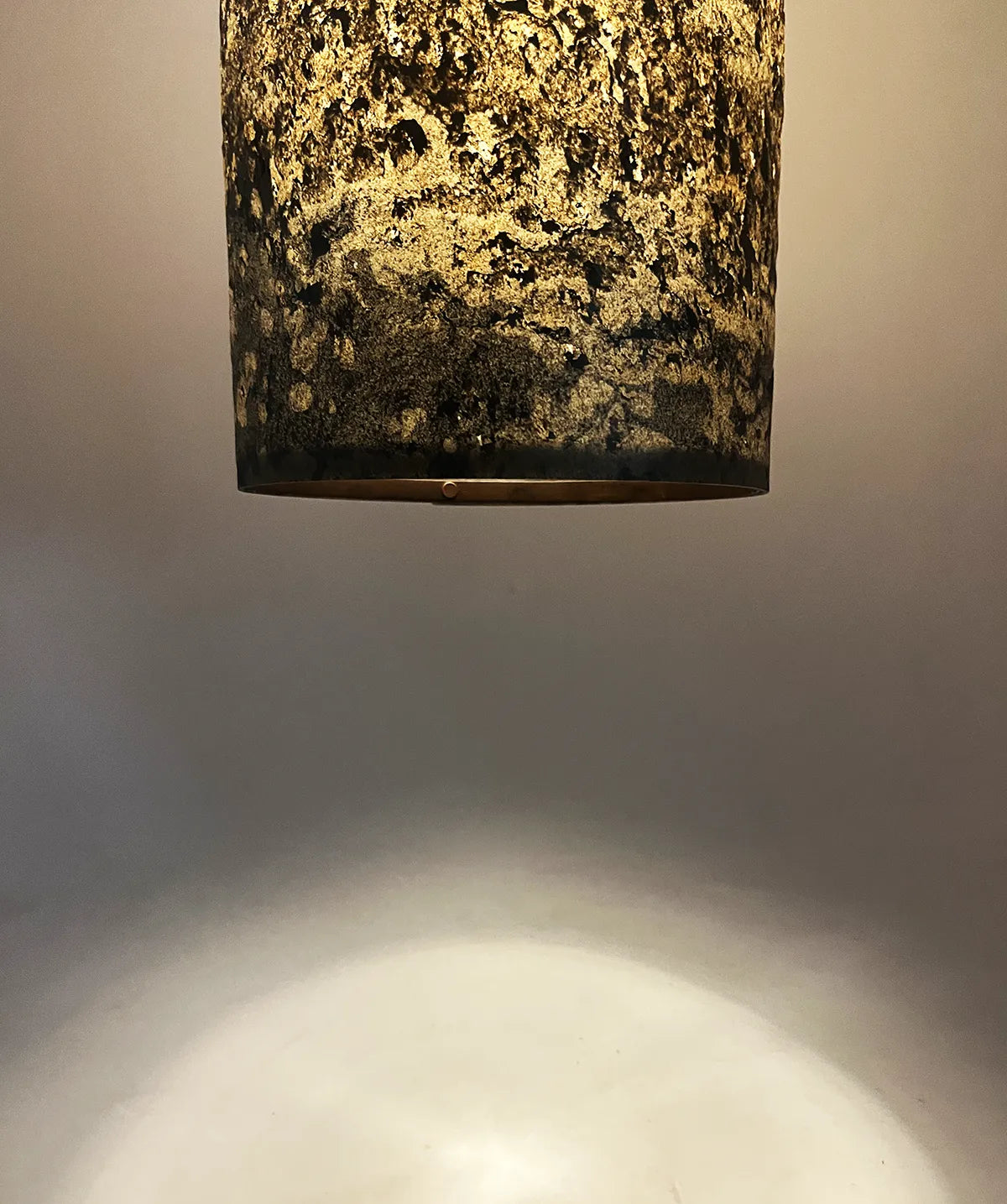 détail de la suspension en feuille d'ardoise rustique Swan allumée, texture minérale. Atelier Maus
