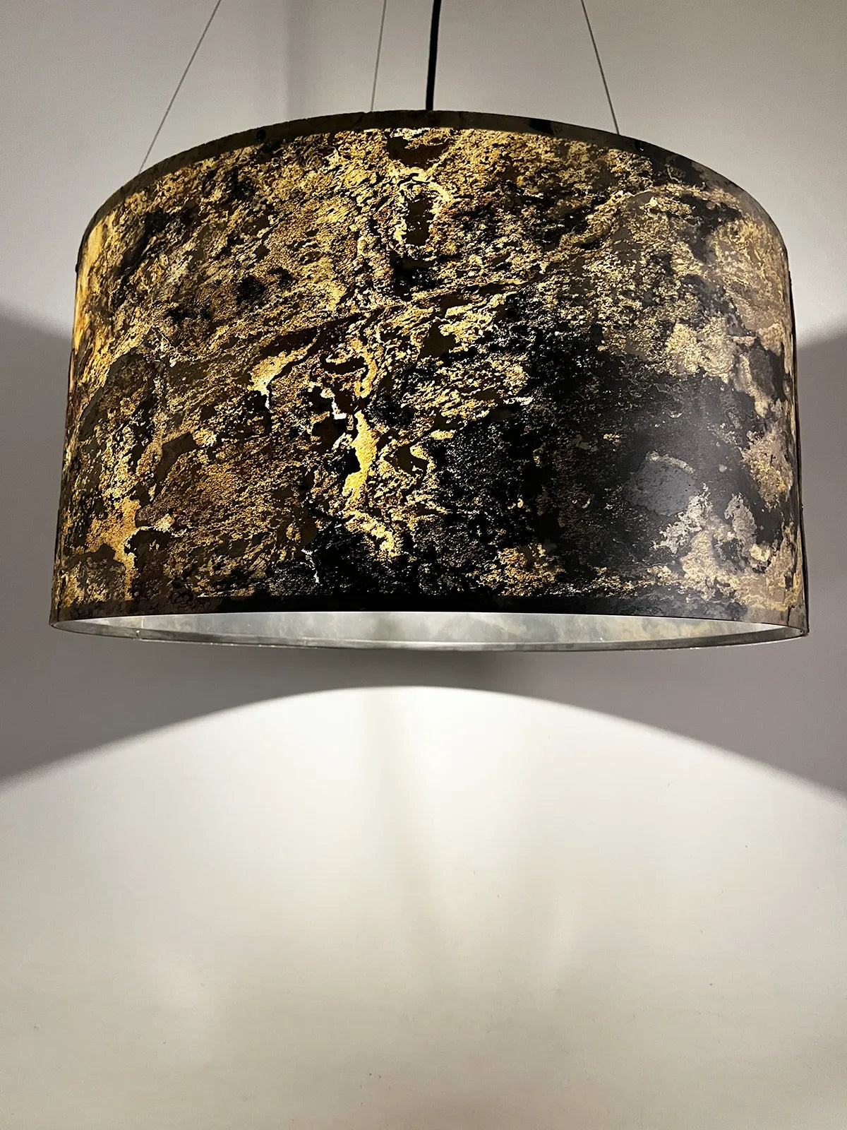 suspension en ardoise rustique Thessalie par l'atelier Maus allumée et refletant des couleurs ocres, beiges et noires très nuancées