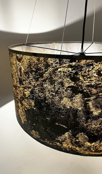 détail de la suspension en ardoise rustique Thessalie par l'atelier Maus allumée et reflets de  couleurs ocres, beiges et noires  nuancées