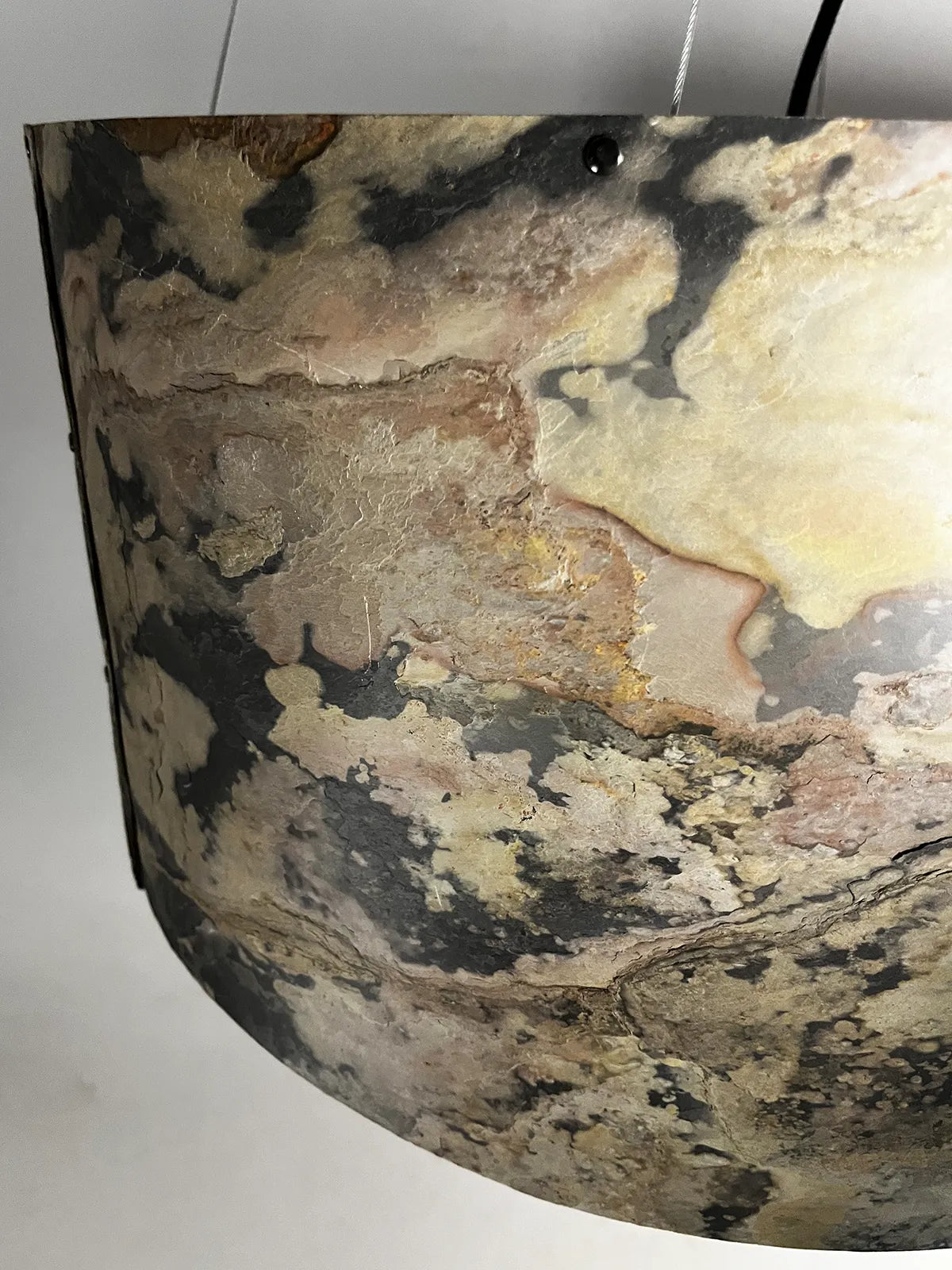 vue de détail de la suspension en ardoise rustique Thessalie par l'atelier Maus . reflets des couleurs ocres, beiges et noires très nuancées et vue de sa texture minérale naturelle